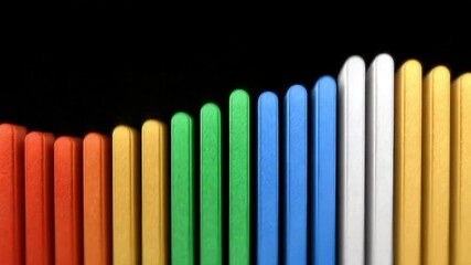 Aufkleber - Harmonic Arrangement: A colorful arrangement of sticks in a row against a black background, showcasing a harmonious blend of vibrant hues.