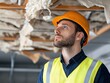 © Moopingz - Construction worker inspects damaged ceiling, wearing safety vest and helmet.