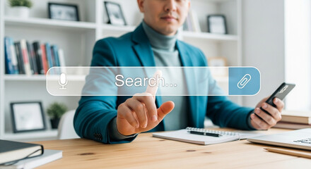 Poster - Man using search bar on screen with phone in hand in office setting with books and laptop on desk