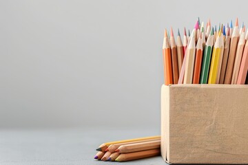 Fototapete - A Collection of Pencils a Box and a Box of Brown Paper Are on a Gray Background