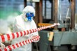 © BESTIMAGE - Man inspector scientist investigate chemical gas leak spill with safety face mask PPE suit in area closed barricade security red white tape. danger area infected toxic leak spill cross stripe ribbon