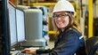 © sambath - A woman wearing a white hard hat and safety glasses, seated at a computer in a factory setting, with a computer monitor and keyboard in front of her.