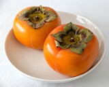 Fresh ripe persimmons in full white plate isolated background