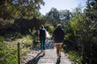 © Cavan Images - Hikers walking on wooden elevated path in forest preserve