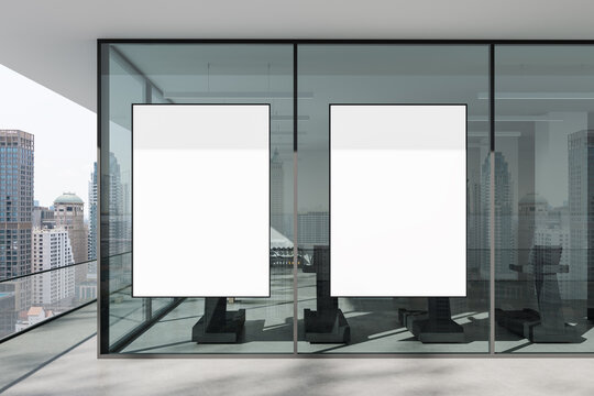 Blank vertical posters on glass wall in modern building interior with cityscape reflection in daylight setting, ideal for clean advertising mockup display. 3D Rendering