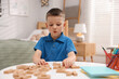 © New Africa - Dyslexia. Little boy learning letters at table indoors