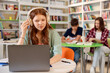 © New Africa - Student with laptop studying at table in library