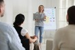 © New Africa - Woman giving public speech near whiteboard in front of audience indoors