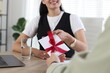 © New Africa - Money bonus. Boss giving envelope with bow to employee in office, closeup
