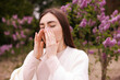 © New Africa - Woman suffering from seasonal pollen allergy near blossoming shrub on spring day