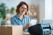 © zamuruev - Woman smiles while printing shipping labels on thermal printer in airy home office with minimalistic decor. Bright environment encourages productivity. Concept of e-commerce, logistics, online retail