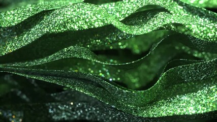 Poster - Luxurious green ribbons glittering and waving smoothly, creating elegant festive atmosphere with vibrant shimmering light on dramatic black background