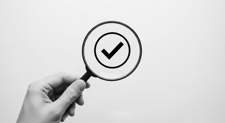 Poster - A hand holding a magnifying glass over a check mark in black and white on a white background