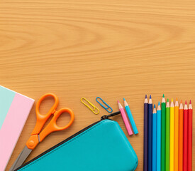 Aufkleber - Flat lay of school supplies on wood surface: scissors, pencil case, colored pencils, paper clips, notepad.  Showcase of back-to-school theme, ideal for stationery advertising
