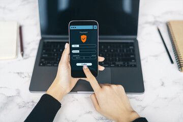 Poster - Person using smartphone to make secure online payment with laptop on desk in bright workspace background, emphasizing digital transaction safety.