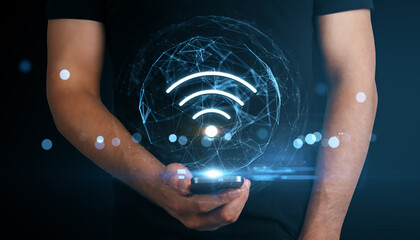 Poster - Man holding smartphone displaying glowing digital Wi-Fi icon with holographic network on dark blue background, symbolizing modern wireless technology.