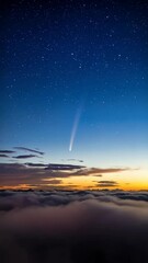 Wall Mural - Bright comet soars through a deep blue starry sky above cloud formations during a golden sunset.