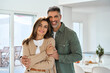 © insta_photos - Smiling affectionate loving middle aged couple, happy romantic mature older Latin man and woman in their 50s hugging looking at camera standing together in modern kitchen at home. Portrait.