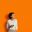 © gerson - Mujer sonriente sosteniendo teléfono móvil con fondo geométrico