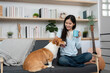 © wichayada - Relaxing with Pet. Woman enjoying tea while petting her corgi dog at home.