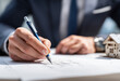 © Ali Murtaza  - A real estate agent is sitting at his desk, looking over the floor plan of an apartment building with a blue pencil and drawing on it. There's also a paper cup of coffee beside him. In front of him li