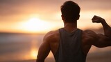 A man flexing his biceps in front of the ocean at sunset