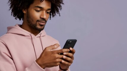 A young man smiles while looking at his phone