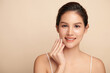 © kitthanes  - A beautiful young Asian woman with clean, fresh skin against a beige background. Skincare, facial treatment, cosmetology, beauty, and spa. An elegant portrait of an Asian woman.