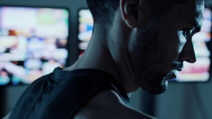 Serious man in dark room with multiple screens, cyber technology concept