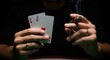 © pansit.me - Hands holding two aces playing cards and lit cigar against black background