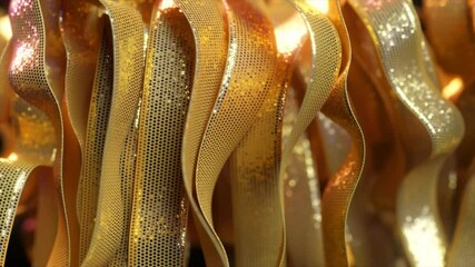Poster - Luxurious golden ribbons with perforated surface and glittering texture flowing smoothly, creating elegant abstract composition with graceful curving motion
