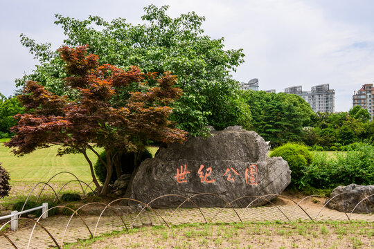 Park entrance marked by a large stone. Established in 2000, this is the largest park in Shanghai with greenery, trees and skyline. Chinese words on the stone translate to Century Park