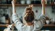 © Larisa AI - A young woman with a messy bun is raising her arms in celebration at home, surrounded by a vibrant kitchen atmosphere, accompanied by a cute dog, expressing joy and enthusiasm.