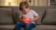 © Pics_With_Love - Caucasian baby boy 2 years old with abdominal pain sitting on sofa in cozy home, both hands on stomach, red glow highlights pain area, evening lighting