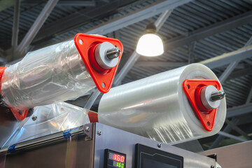 Poster - A roll of plastic polyethylene film is cut by a food packaging machine. Industrial concept background