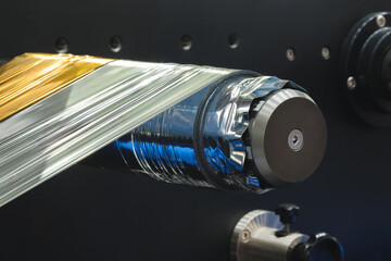 Poster - A roll of plastic polyethylene film is cut by a food packaging machine. Industrial concept background.