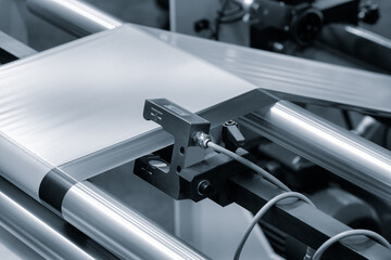 Poster - A roll of plastic polyethylene film is cut by a food packaging machine. Industrial concept background.