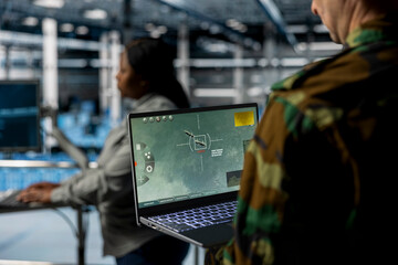 Poster - Close up of military officer in data center looking at missile lock interface displayed on laptop screen. Soldier in army server hub checking target coordinates and crosshair overlay on notebook
