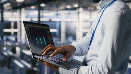 Poster - Engineer and colleague in data center reviewing large language model visualizations on laptop. IT engineering team analyze neural network performance outputs to ensure stable infrastructure operations