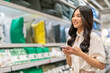 © Art_Photo - Asian woman shopping in home goods store smiling while pushing cart through bedding section, enjoying retail lifestyle, consumer behavior, weekend leisure, home decor at modern market