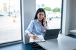 © Apichat - woman is sitting at a table with a laptop and a clipboard
