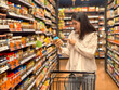 © Apichat - woman is shopping in a grocery store and pointing at a jar of peanut butter