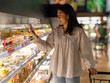 © Apichat - woman is shopping in a grocery store and is holding a container of ice cream
