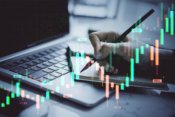 Poster - Business hand writing on notepad near laptop with digital forex chart overlay showing investment analysis and candlestick market data.