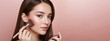 © NeuroCake - Young woman applying blush with makeup brush on pink background. Studio beauty portrait. Cosmetics and skincare concept. Image for poster, banner, wallpaper and advertisement. Portrait with copy space
