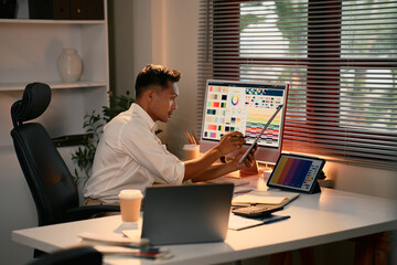 focused graphic designer working on color palettes and digital layouts in a modern office