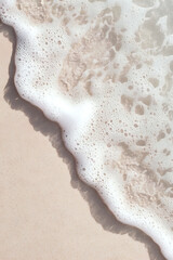 Poster - Gentle ocean foam washing onto beige sand beach creates natural diagonal composition with soft white bubbles and waves for tranquil coastal backdrop.