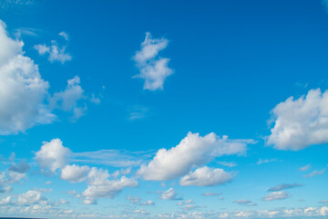 a vast expanse of bright blue sky dotted with fluffy white clouds.several clouds of varying sizes ar