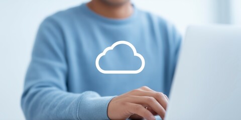 Fototapete - Person in light blue sweater typing on laptop with cloud icon overlay, representing digital technology and online storage solutions in a modern workspace environment