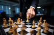 © Sultana - Close-up of businessman's hand moving chess queen, strategic game in office